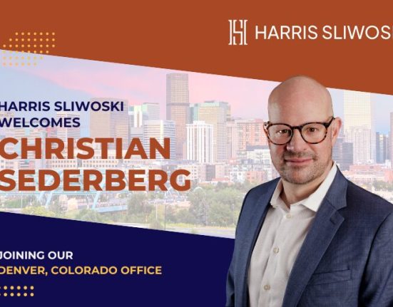A man in a suit and glasses stands in front of a cityscape with text welcoming Christian Sederberg to Harris Sliwoski’s Denver, Colorado office.